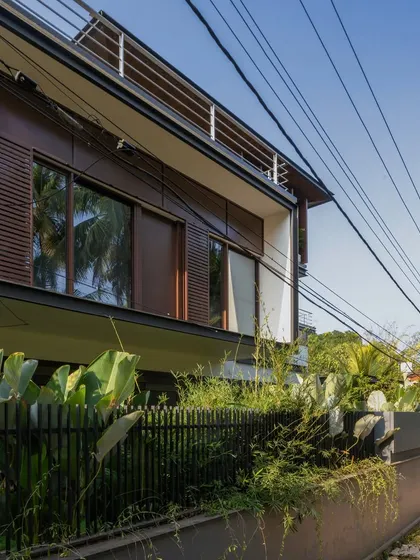 Exterior views of the Mango Tree Yard home, highlighting its contemporary form, clean lines, and the use of screens for privacy and ventilation.