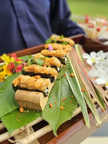 A tray of our unique sushi appetizers, presented on a bed of fresh leaves and flowers.
