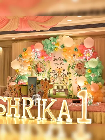 A "Wild One" jungle stage featuring a fun jeep prop for photos, surrounded by pastel balloons and cute animal friends.