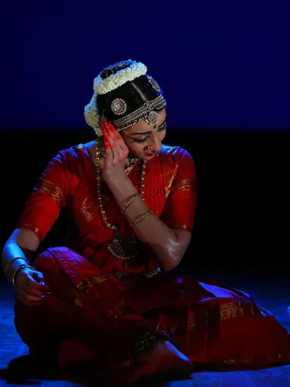 A seated moment of quiet devotion, where the dancer listens to the divine call. The subtle lighting and focused expression are meant to draw the audience into the spiritual narrative.