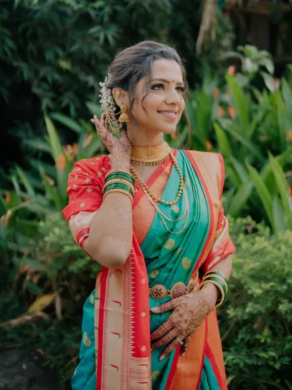 A smiling bride in her beautiful saree. The makeup is fresh and dewy, with a touch of flowers in her hair to complete the look.