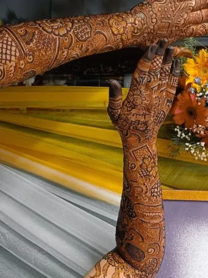 A stunning shot of a bridal henna design, with one arm raised to show the detail. The floral and geometric patterns create a beautiful contrast.