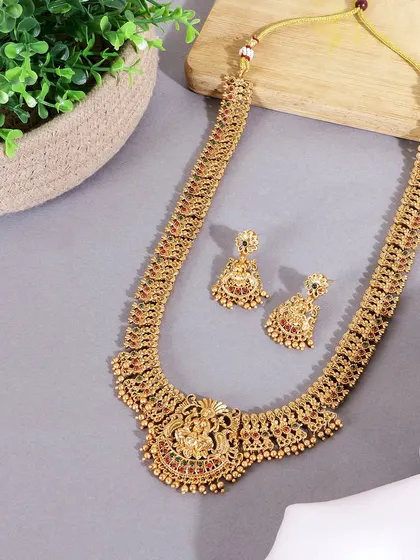 A flatlay of a traditional temple jewelry necklace set. The simple grey background and subtle props ensure that the focus remains entirely on the intricate design of the jewelry.