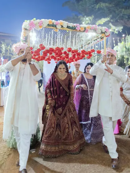 The bride's grand entrance under a beautiful phoolon ki chaadar made of red carnations. A traditional and emotional moment captured perfectly.