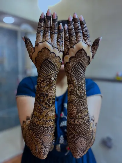 A peek-a-boo pose showcasing the full bridal henna design with its intricate patterns.