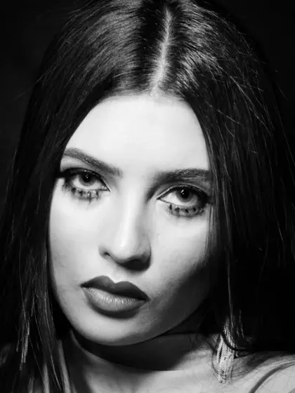 An intense, direct gaze in this black and white portrait, where the dramatic lower lash makeup is a key feature.