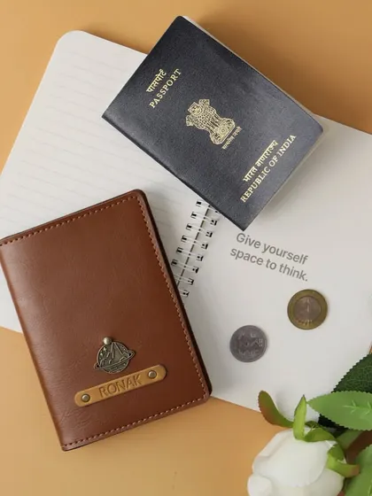 This personalized passport cover in brown vegan leather is a classic travel accessory. It's customized for "Ronak" with a ship's wheel charm, perfect for someone who loves adventure.