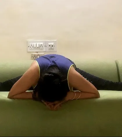 Making the best use of available resources. Here, I am using my sofa to deepen the stretch in a wide-legged forward fold (Upavistha Konasana).