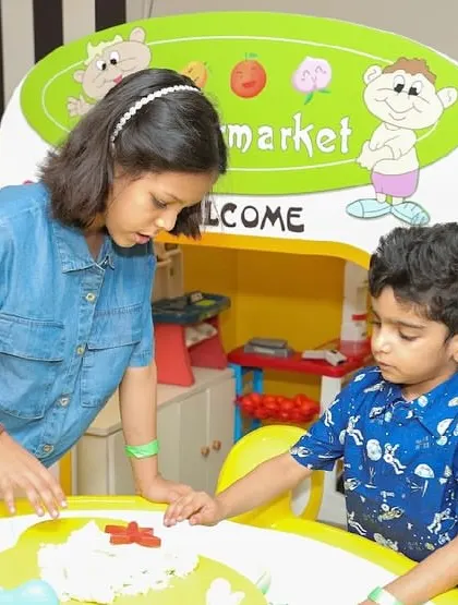 A staff member helps a young boy with a creative activity at the sand table.