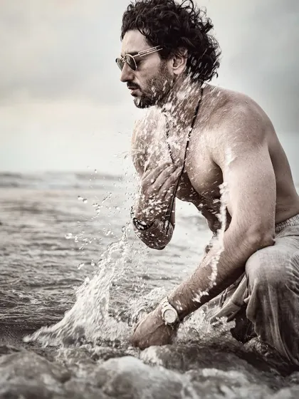 An action shot of Shaad Randhawa at the beach, using a monochrome filter to emphasize the texture of the water and the dramatic mood.