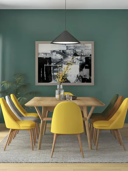 A fresh and modern dining room with a beautiful green-teal accent wall. The bright yellow chairs add a cheerful pop of color, creating a happy and inviting space for meals.