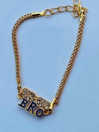 A close-up of the "BRO" rakhi featuring cool sunglasses. The sparkling stones and dark enamel make this a standout piece.