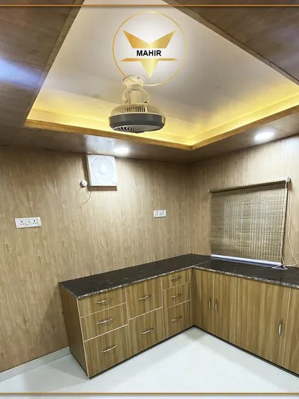 A container is a blank canvas. Here, we've installed a complete kitchen and pantry, featuring wood-finish cabinetry, a granite countertop, and integrated ceiling lights, proving that portable structures don't have to compromise on comfort or style.