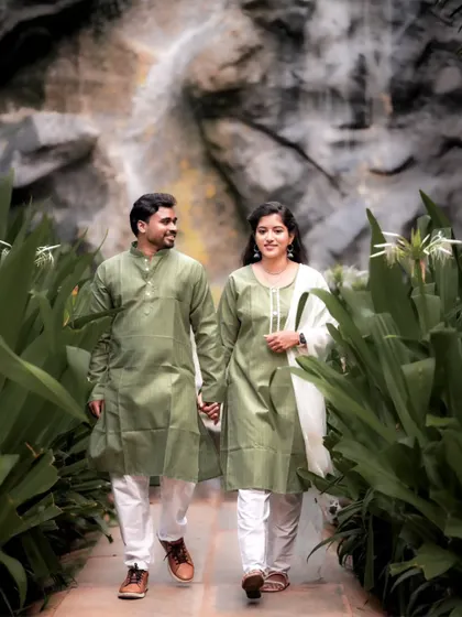 A lovely shot of a couple in matching green kurtas walking hand-in-hand through a garden path.