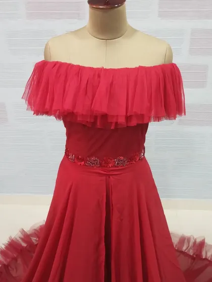 A detail shot of the off-shoulder gown's bodice, featuring a ruffled tulle neckline and an embellished belt for a touch of sparkle.