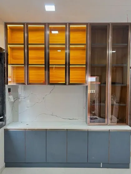 A budget-friendly crockery unit design that doesn't compromise on style. I used a mix of wood-finish laminate and tinted glass with profile lighting to create a high-end look.