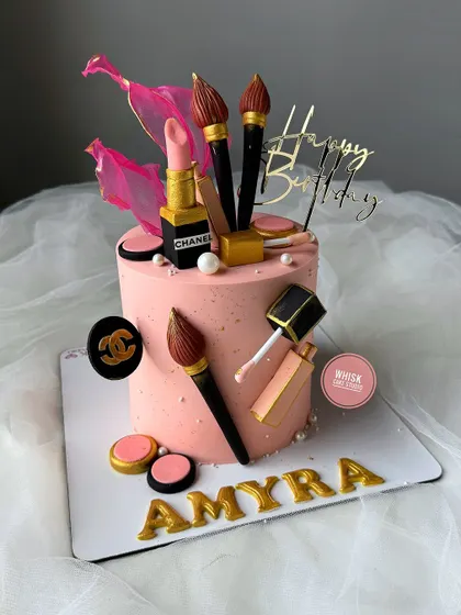 A chic makeup-themed cake for a beauty lover. This pink cake is adorned with handcrafted, edible makeup items like lipstick, brushes, and nail polish.