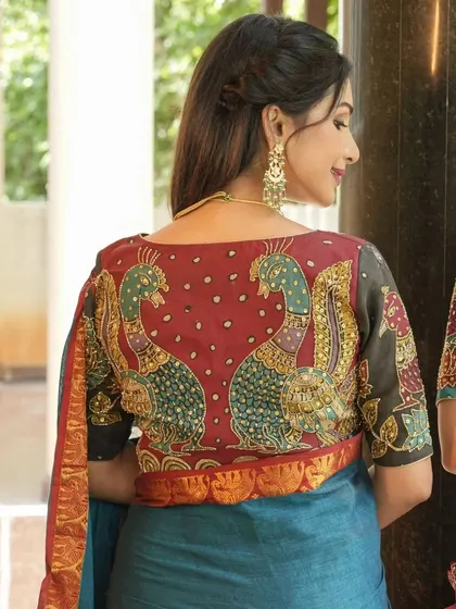 This blouse showcases a symmetrical design of two peacocks, hand-painted in the Kalamkari style and embellished with beadwork. The rich colors and detailed art make it a truly festive piece.