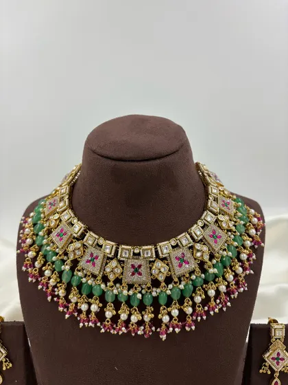 The Divya Premium Antique Gold Necklace set. This piece features unique square motifs with Meenakari work, layered with green and ruby beads for a colorful yet traditional look.