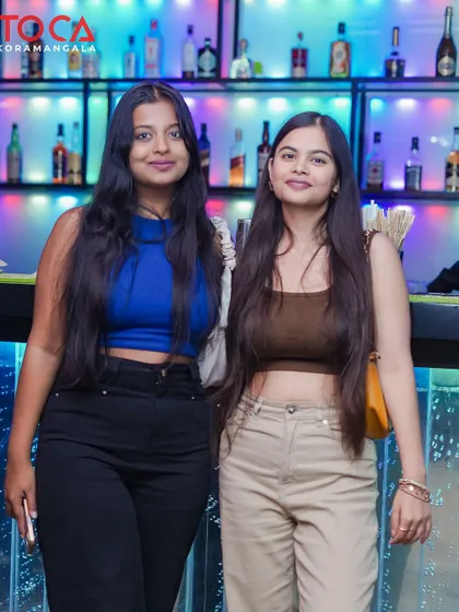 Two friends posing for a photo by the bar, enjoying their night out.