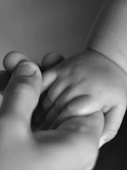 A simple yet profound black and white close-up of a baby's hand gently holding an adult's finger, symbolizing trust, connection, and the beauty of new life.