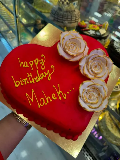 A vibrant red heart-shaped cake personalized for Mahek's birthday. The golden-dusted white roses add a touch of luxury and elegance to this lovely celebration cake.