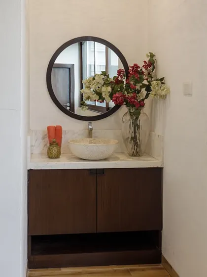 The bathroom for the private gym space. We kept it simple and elegant with a dark wood vanity, a stone vessel sink, and a large round mirror to complement the home's overall aesthetic.