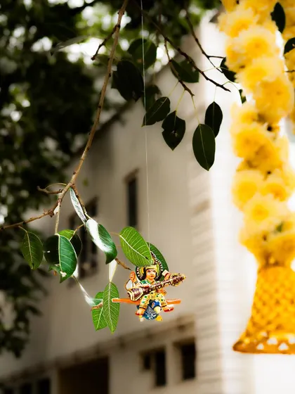 A tiny, hand-painted figurine of a deity playing a veena hangs delicately from a tree branch. These whimsical touches are part of my styling philosophy, adding a layer of charm and discovery to an event space.