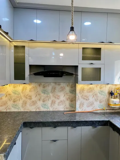 This kitchen features handleless cabinets for a super clean look. The leafy patterned backsplash adds a touch of nature to the modern design.