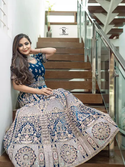 A graceful pose on the stairs, showing off the full, flowing skirt of the heavily embroidered peacock blue lehenga.
