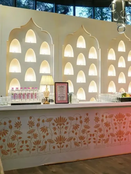 This elegant bar was custom-built for a classic wedding, featuring a backdrop of softly lit Mughal-style arches and a counter decorated with a golden lotus pattern.
