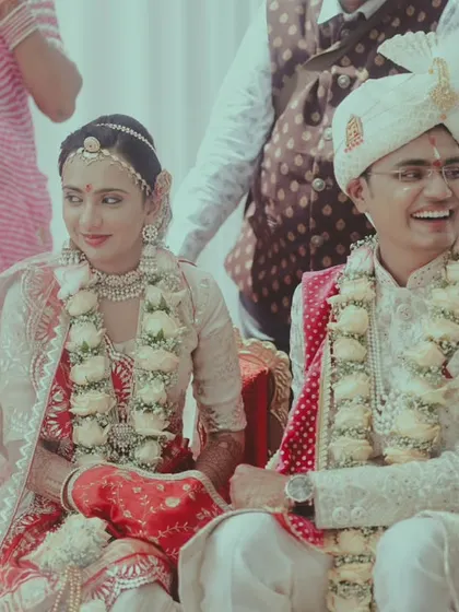 A candid moment during the wedding ceremony, with the groom smiling as he sits beside his bride.