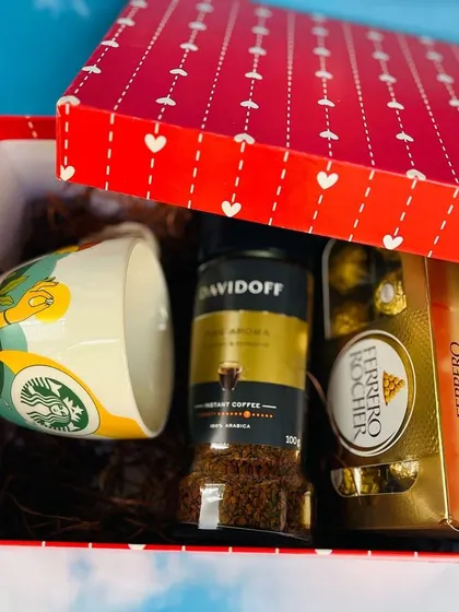 A perfect gift for a coffee lover. This red heart-patterned box contains a Starbucks mug, a jar of Davidoff coffee, and Ferrero Rocher chocolates.
