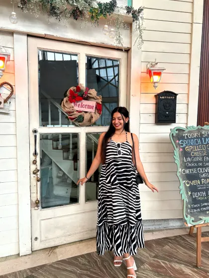 A guest poses happily at our entrance, ready to step inside for an experience filled with French flair and delicious food.