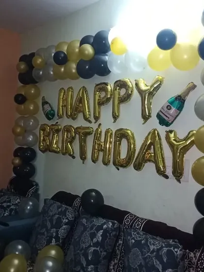 A simple wall decoration for a home birthday party, using gold foil 'Happy Birthday' letters and a black and gold balloon garland.