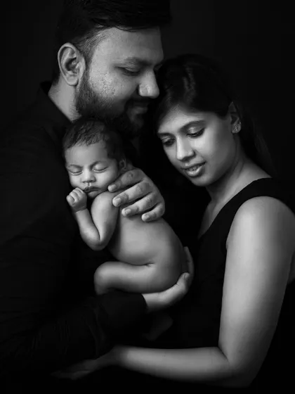 A stunning black and white fine art portrait of a new family. The dramatic lighting and their loving expressions create a deeply emotional and timeless heirloom.