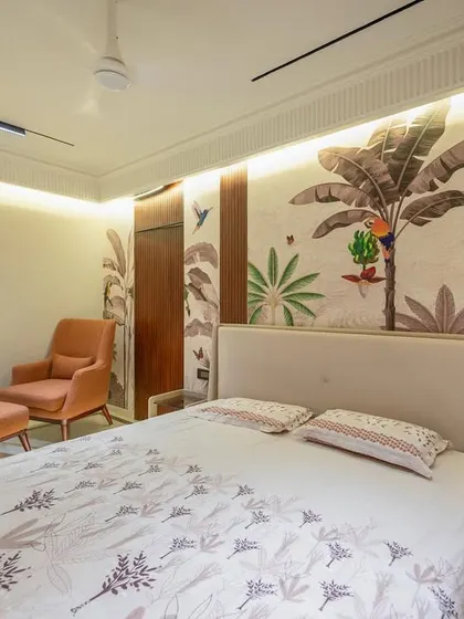 This bedroom features a custom hand-painted mural behind the bed, creating a playful yet serene tropical escape. The furniture, including the upholstered bed and armchair, was designed to align with the contemporary, nature-inspired theme.