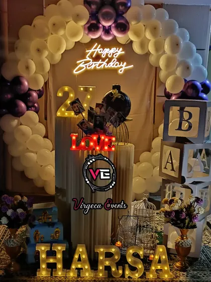 A purple and white birthday decoration with personalized photo displays on the pedestals, adding a lovely personal touch.