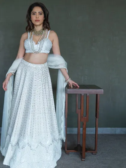 Another angle of the stunning ivory lehenga, showing the beautiful drape of the skirt and the layered pearl necklaces that complete the look.