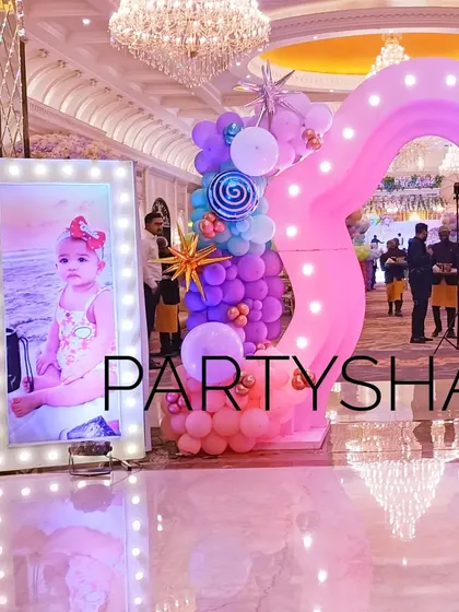 A large, illuminated photo frame and a whimsical pink arch create a beautiful photo opportunity at the party entrance.