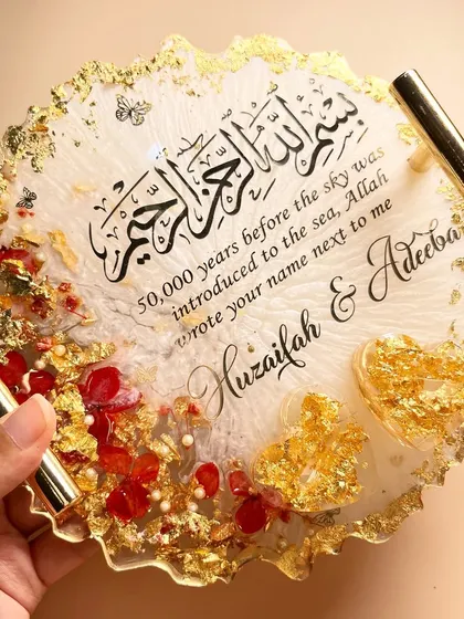 A hand holding the red and gold ring tray to show its size and glossy finish.