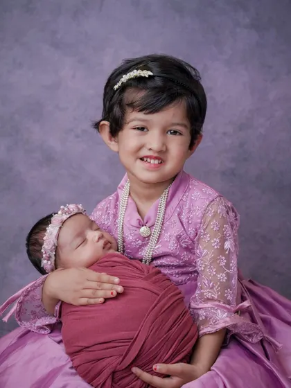 Dressed in their finest, a big sister proudly holds her new baby. These are the moments of pride and new responsibility that I love to document.