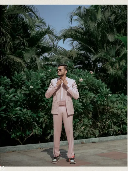 The groom looking cool and stylish in his pink suit and sunglasses against a tropical background.
