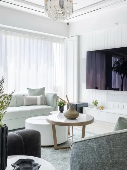 A wider view of the luxury living and dining space, showing how the calming blue palette and intricate wall moulding create a cohesive and elegant environment.