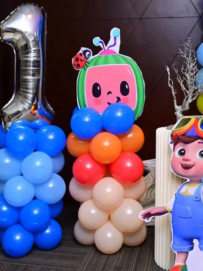 A detailed shot of the Cocomelon decor elements. The balloon pillars are topped with character cutouts, adding height and visual interest to the overall party setup.