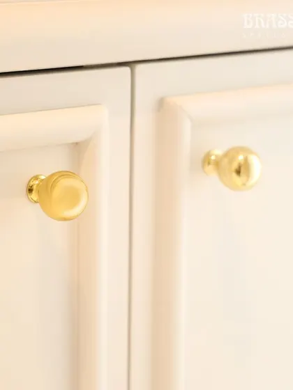 A close-up of our Sphere knob in a Polished Brass finish on a white cabinet. This simple, elegant detail adds a touch of luxury and tradition, reflecting our client's appreciation for India's rich cultural heritage.