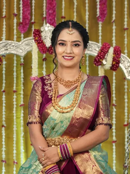 A smiling portrait of Harshitha at the naming ceremony. Her makeup is fresh and enhances her natural glow.