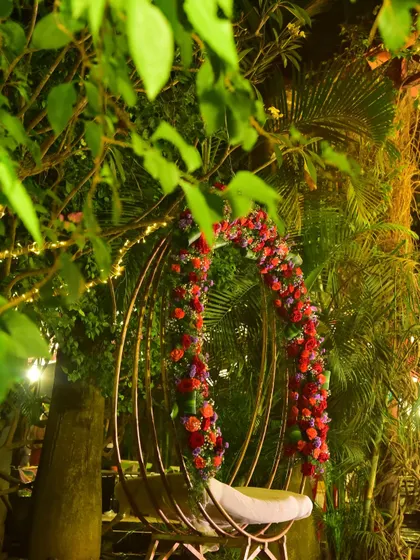 A romantic swing decorated with red flowers, perfect for an outdoor evening event. It provides a lovely photo spot for the couple.
