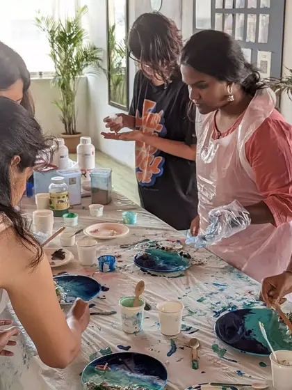 A group of participants engrossed in a resin art workshop, learning how to create beautiful ocean wave effects.