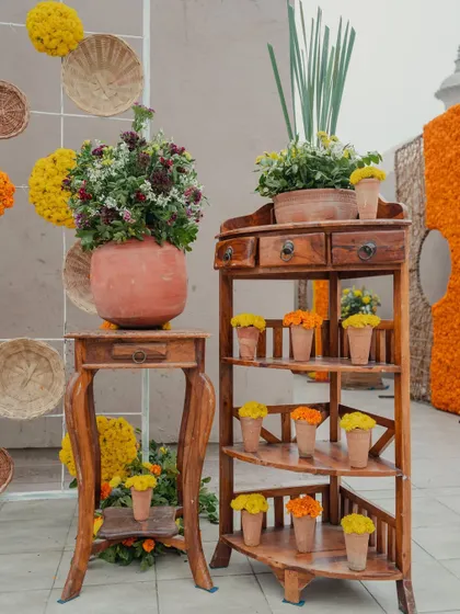 A beautiful corner with rustic wooden furniture and terracotta pots filled with marigolds and other wildflowers, adding a touch of earthy charm.